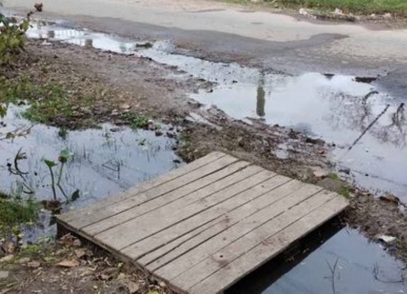 Vecinos ponen tablas para llegar a la vereda de su casa